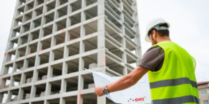 Projeto de instalações elétricas: homem olhando projeto elétrico na obra