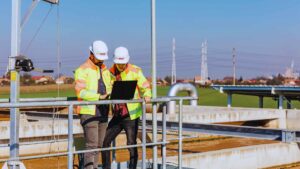 Engenharia elétrica e civil para saneamento: imagem de engenheiros olhando projeto em usina de tratamento de água
