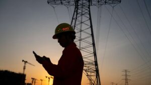 Empresa de instalações elétricas industriais em Curitiba: imagem de gestor em obra industrial com torre de energia de alta tensão